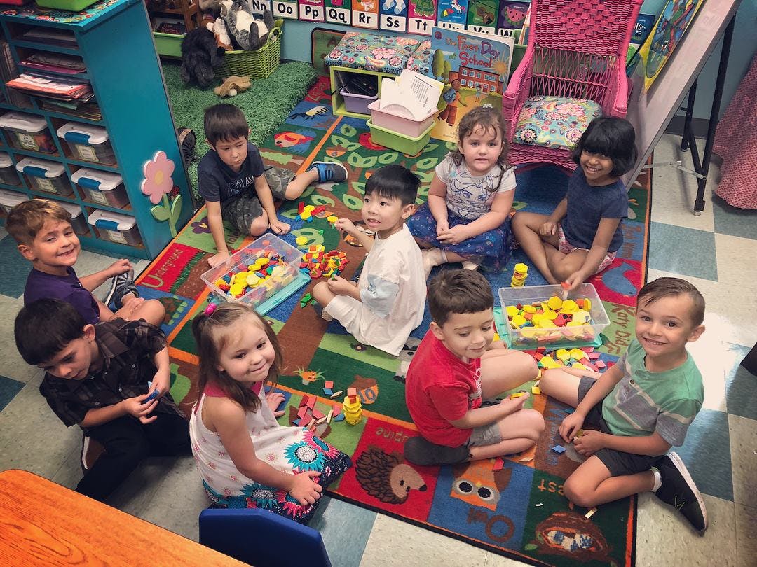 Group of children playing on a colorful rug in a classroom