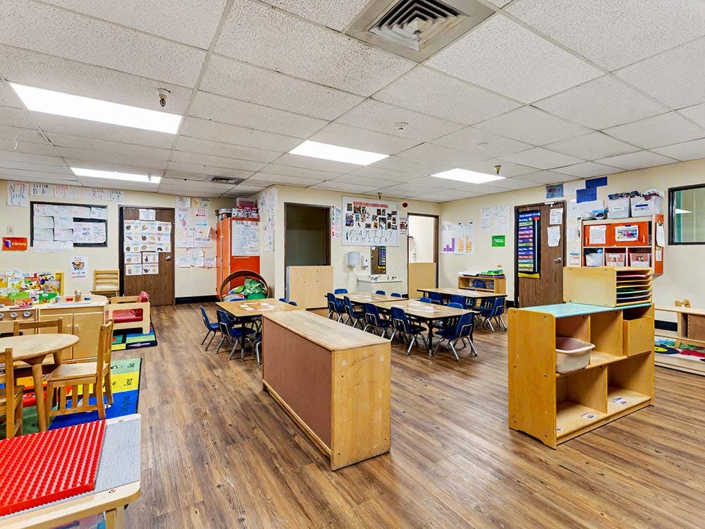 Empty classroom with small tables and chairs, and learning materials