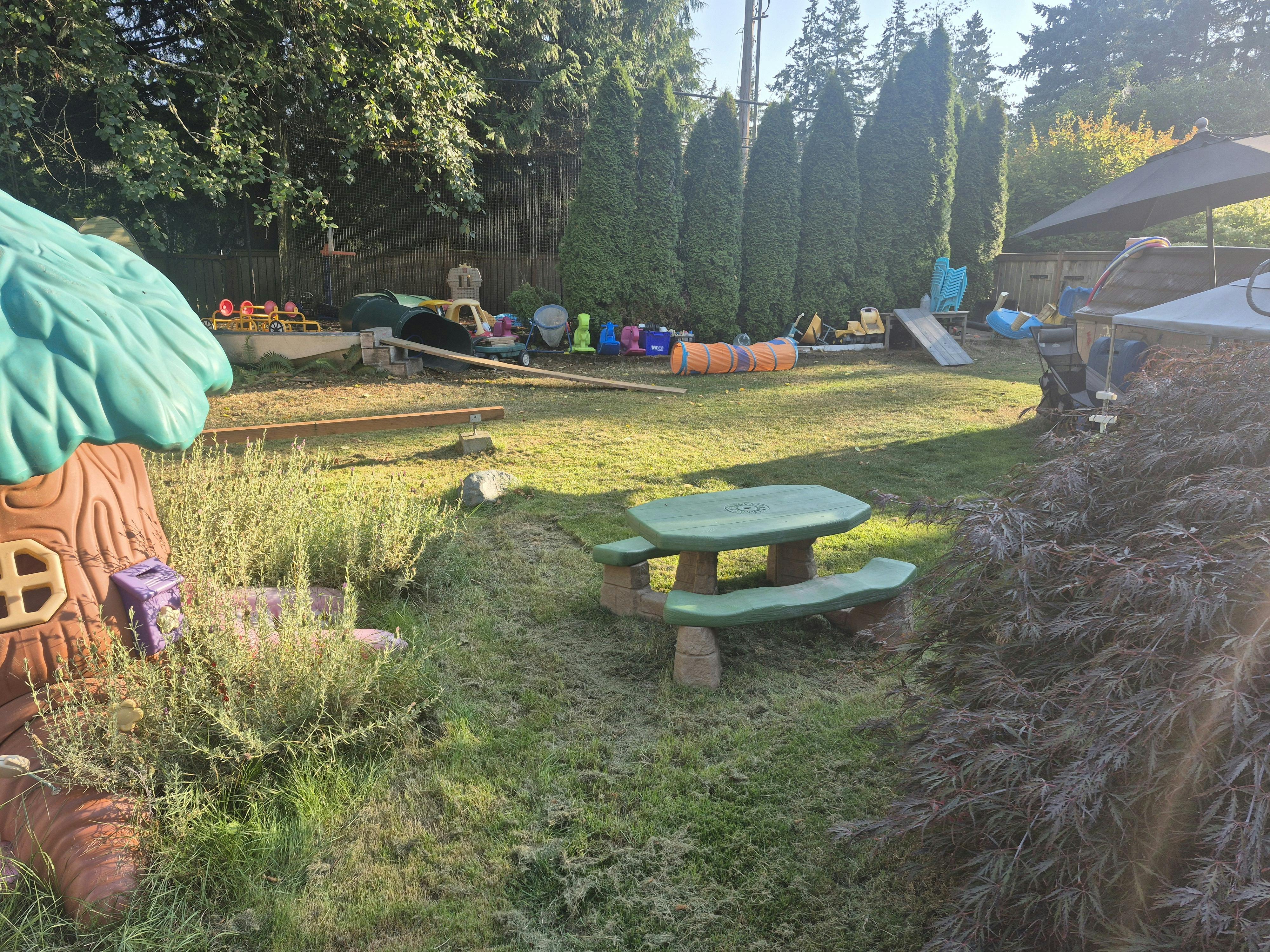 Outdoor play area with a green picnic table and playhouse