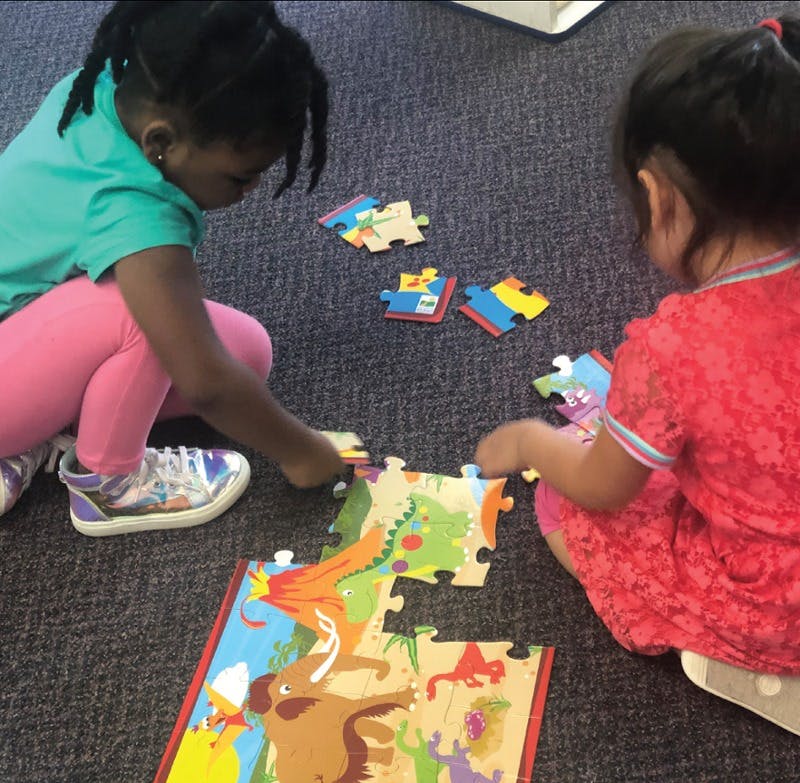 Two children on the floor assembling a large puzzle
