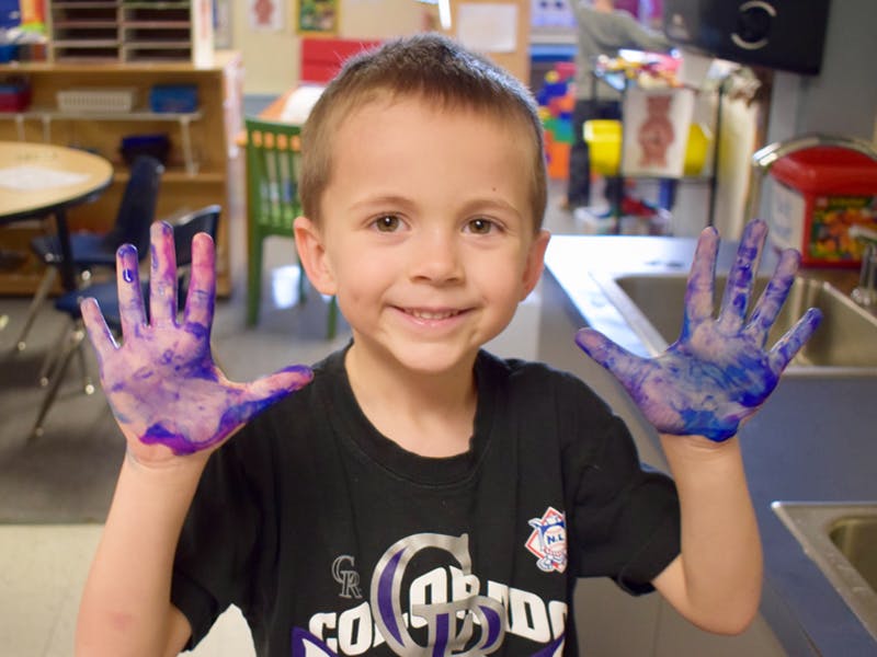 Child with hands covered in paint