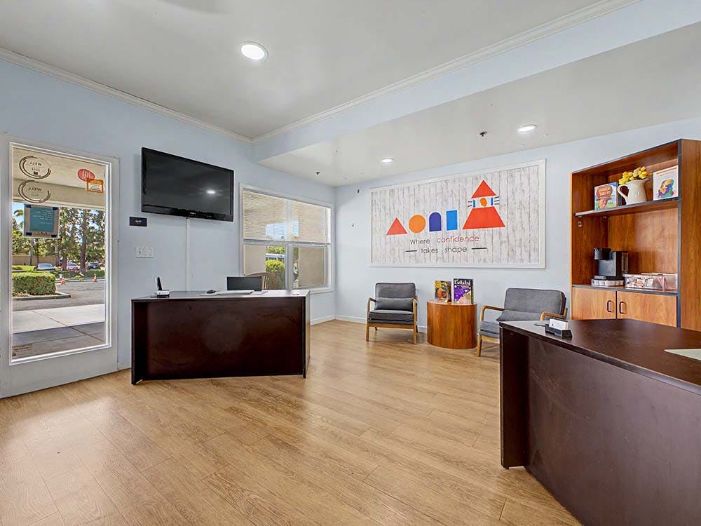 Reception area with a desk, chairs, and a sign that reads "where confidence takes shape"