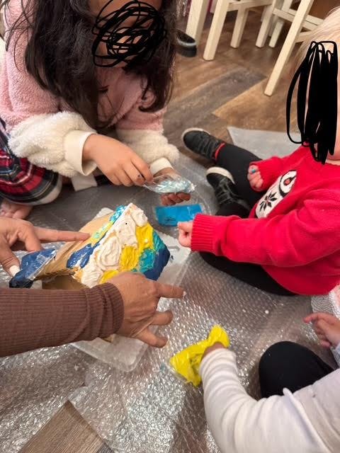 People decorating a cake with colorful frosting