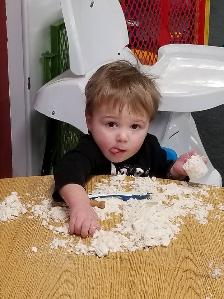 Child playing with flour on a table