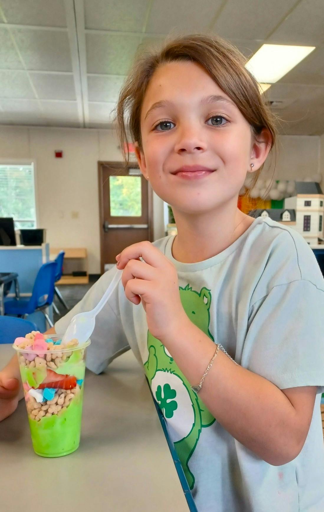 Child holding a spoon next to a colorful dessert cup