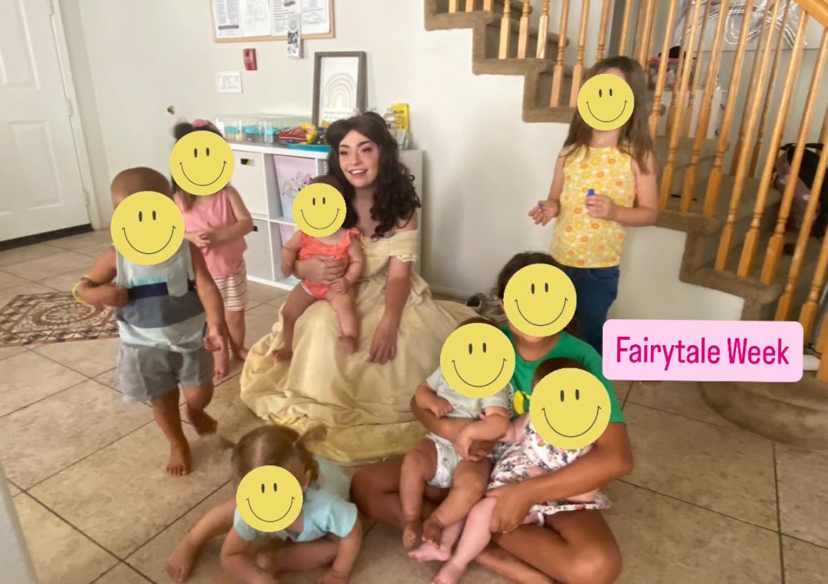 Person in a long dress surrounded by multiple children, text "Fairytale Week"