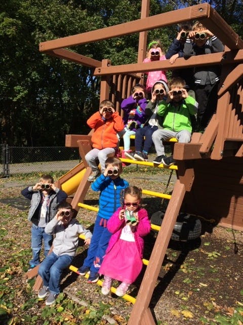 Children on a playground structure looking through binoculars