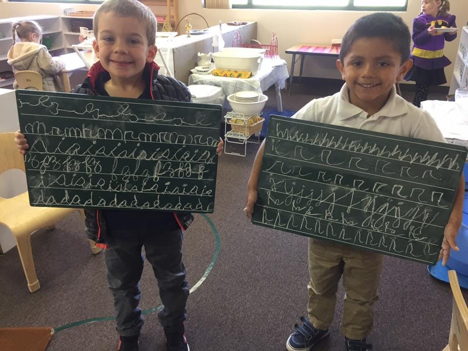 Two children holding chalkboards with writing on them