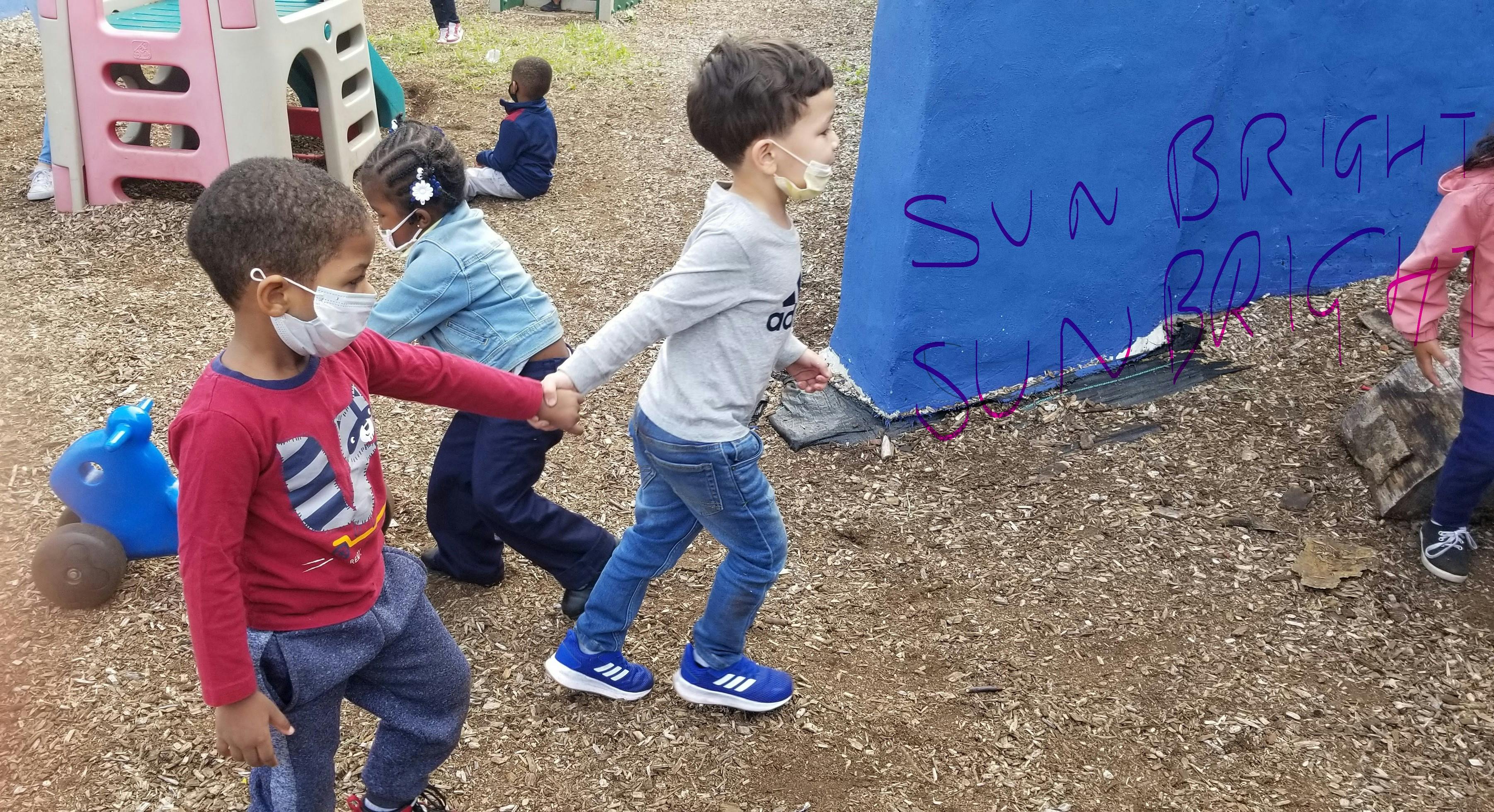 Three children holding hands and walking outdoors