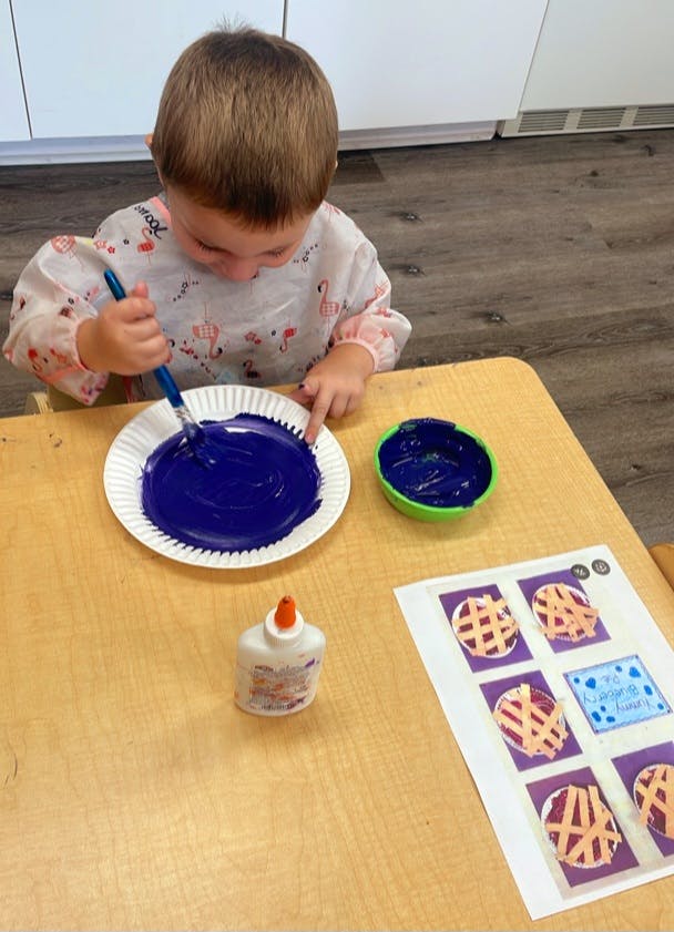Child painting on a paper plate at a table