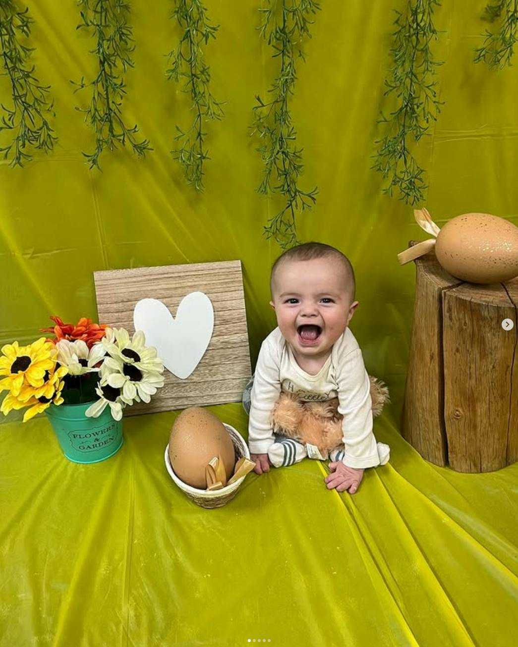 Laughing child sitting with a stuffed animal and Easter decorations