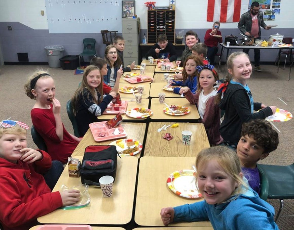 Children sitting at tables with plates of food