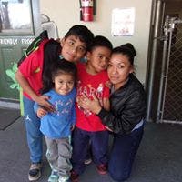 Four people posing for a photo, three children and one adult