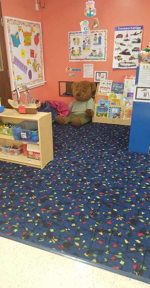 Teddy bear sitting on the floor in a classroom