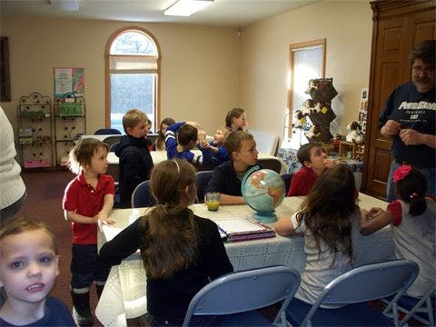 Children and adults gathered around tables in a room