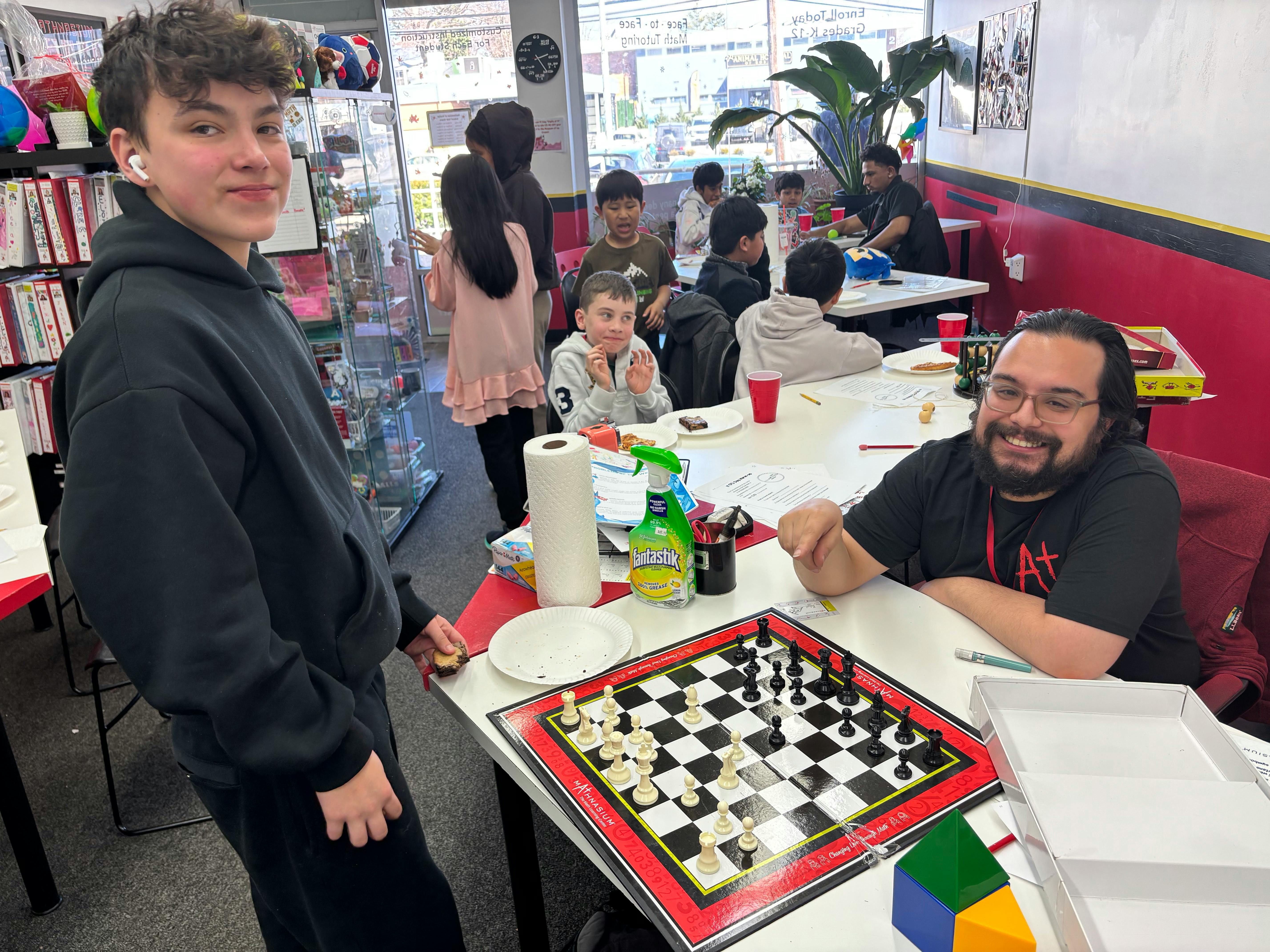 People gathered around tables playing chess and eating snacks