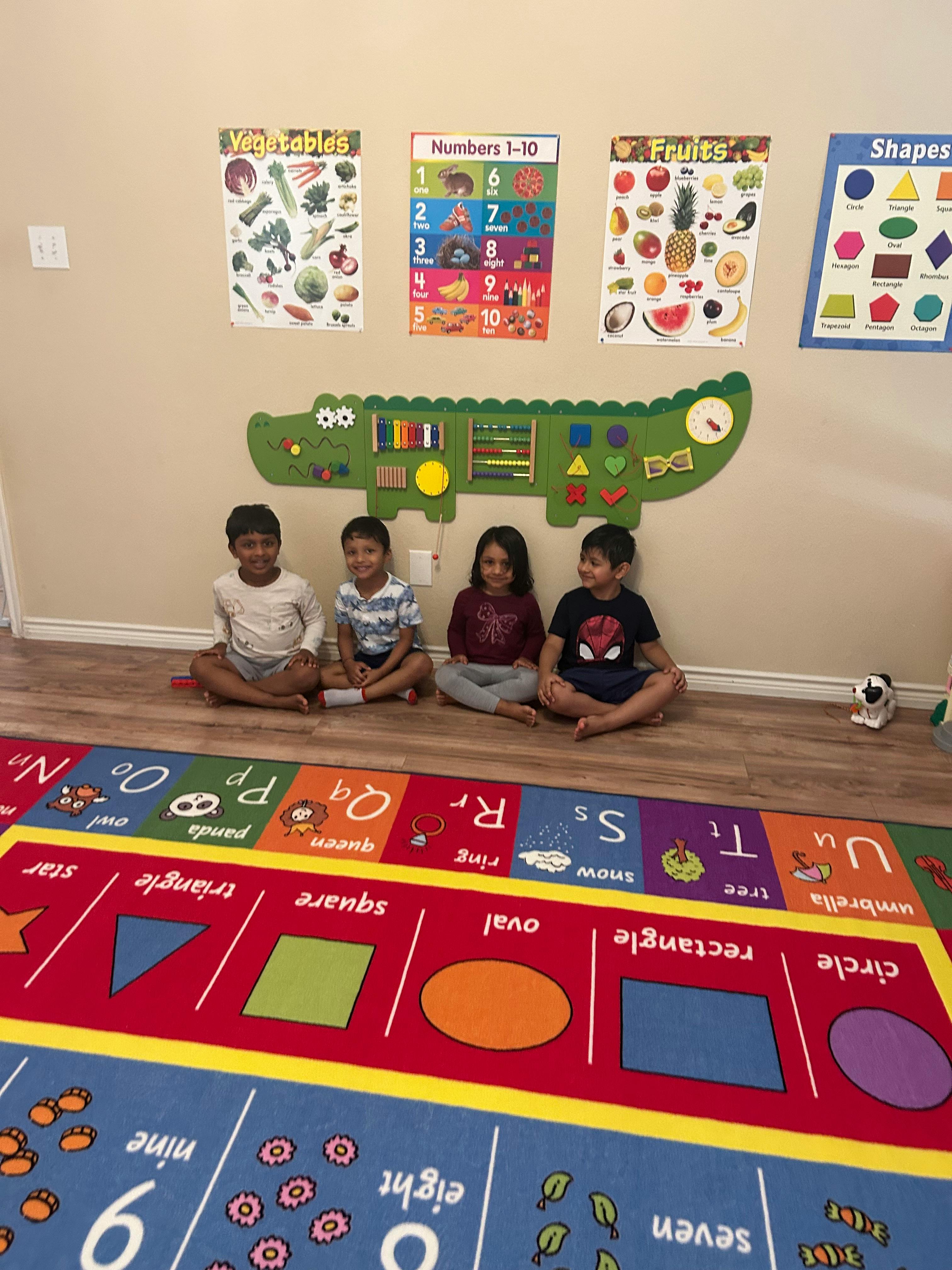 Four children sitting on the floor in front of educational posters