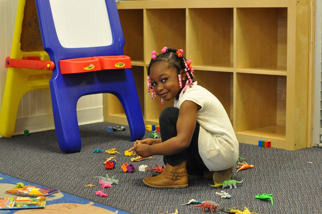 Child crouching on floor playing with small toys