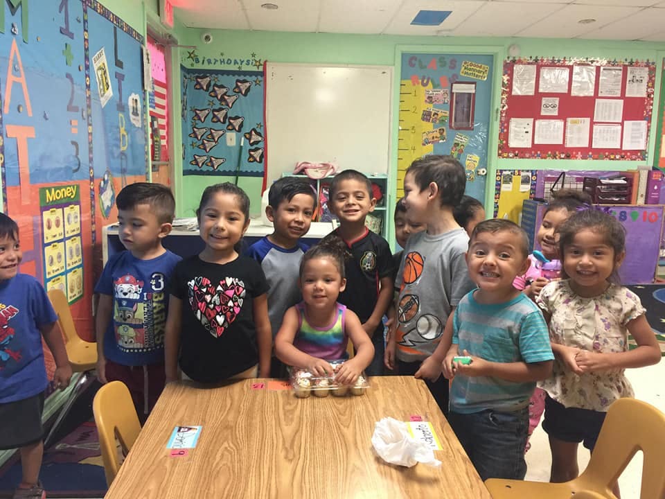 Group of children standing around a table in a classroom