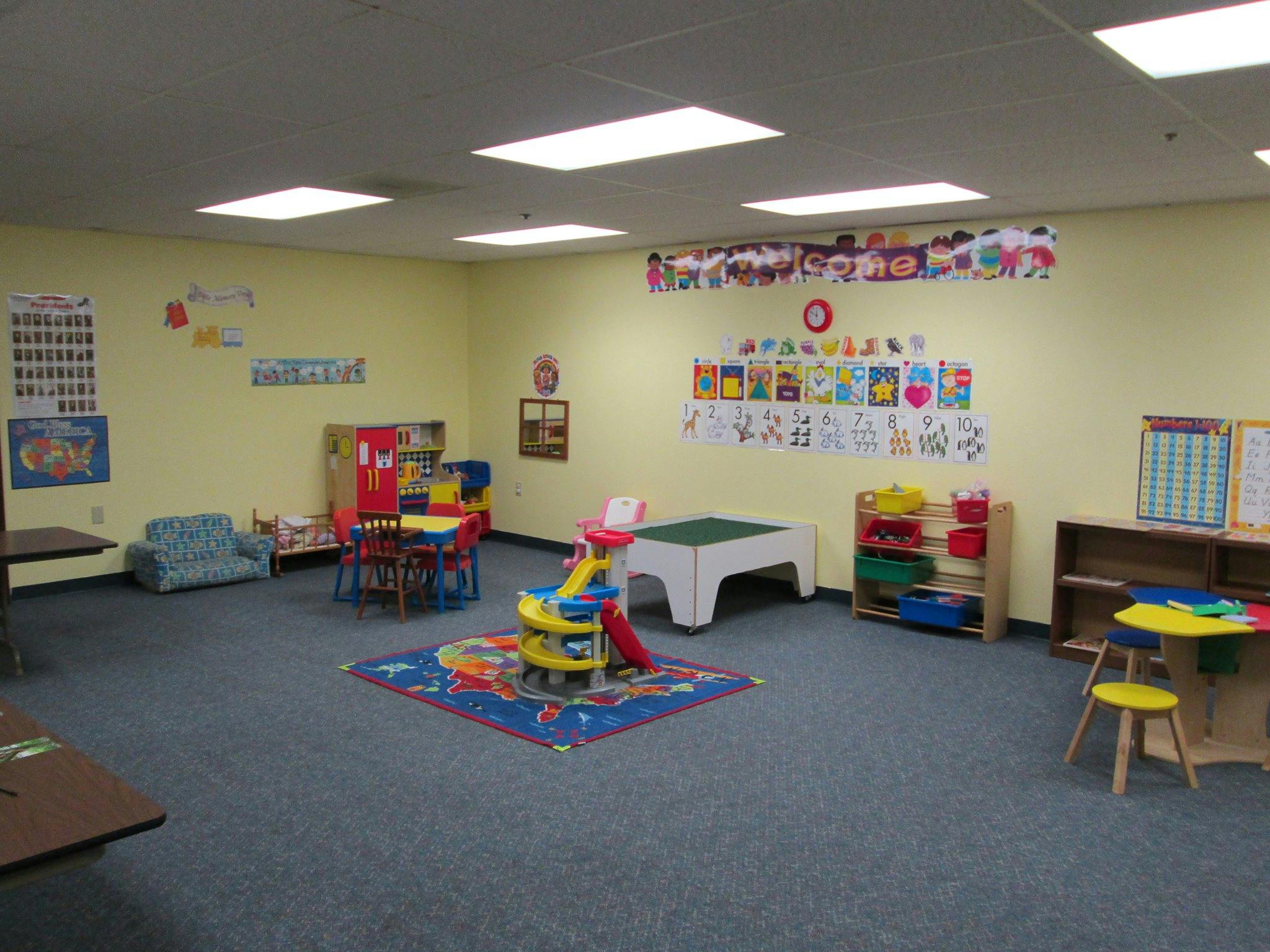 A classroom with small tables, chairs, and toys