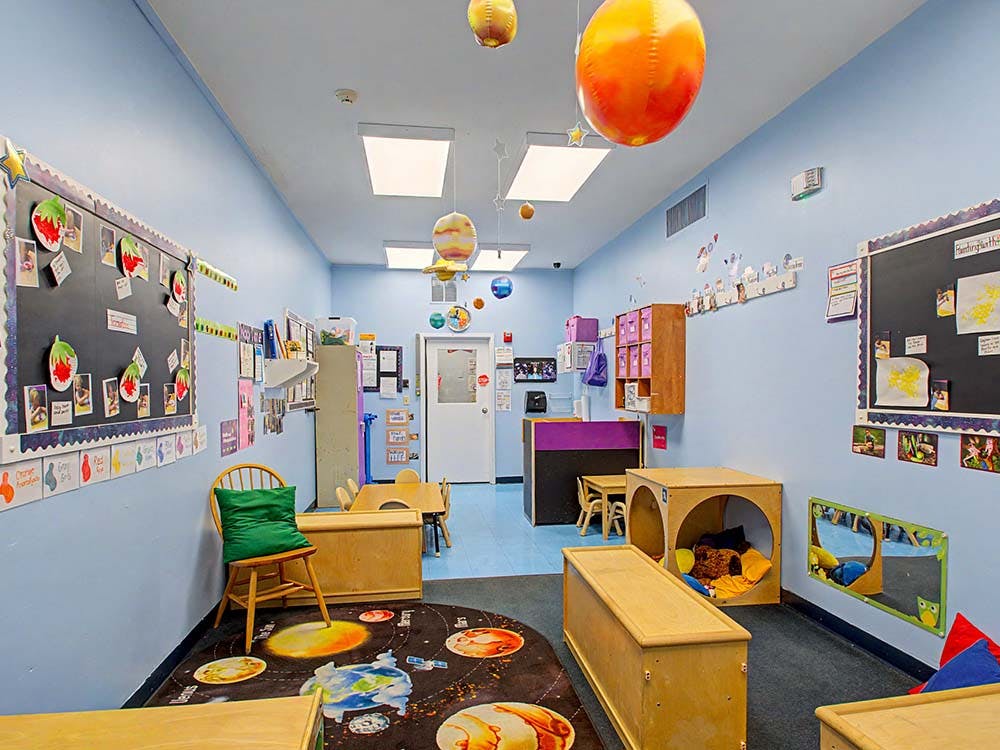 Classroom with blue walls, a planet rug, and celestial decorations hanging from the ceiling