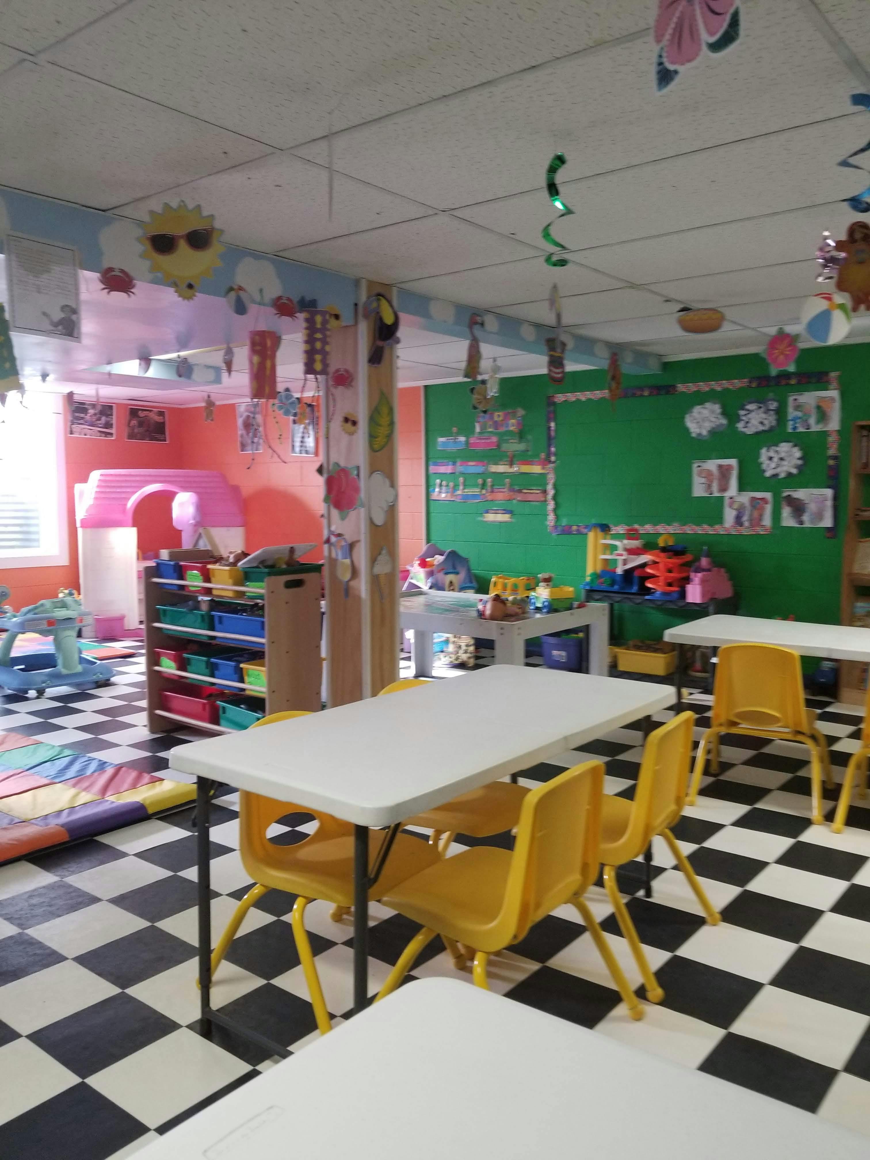 Classroom with small tables and chairs, toys, and colorful decorations