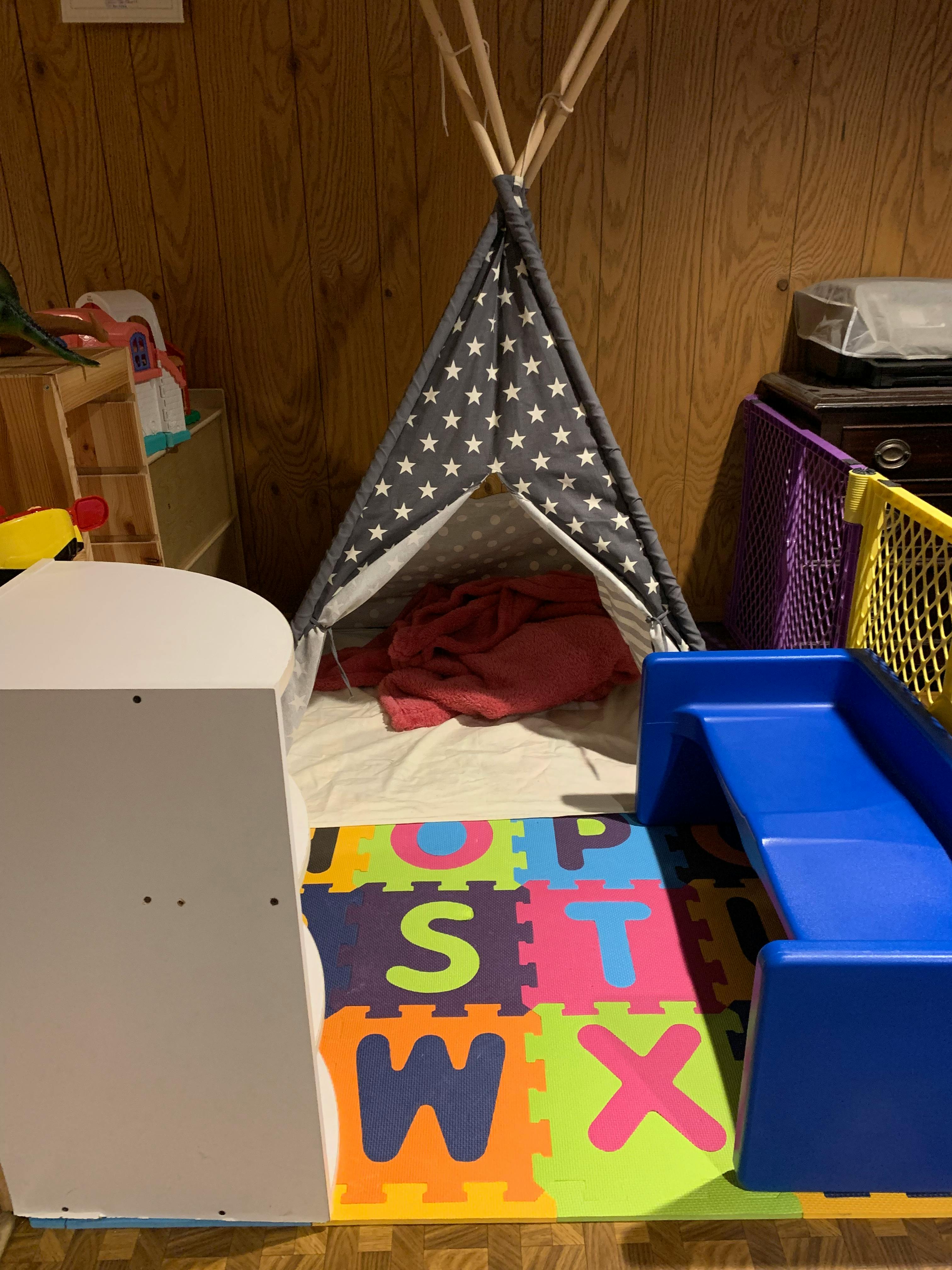 Playroom with a teepee, alphabet mat, and blue slide