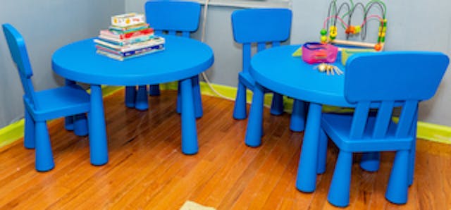 Two blue tables and chairs with books and toys