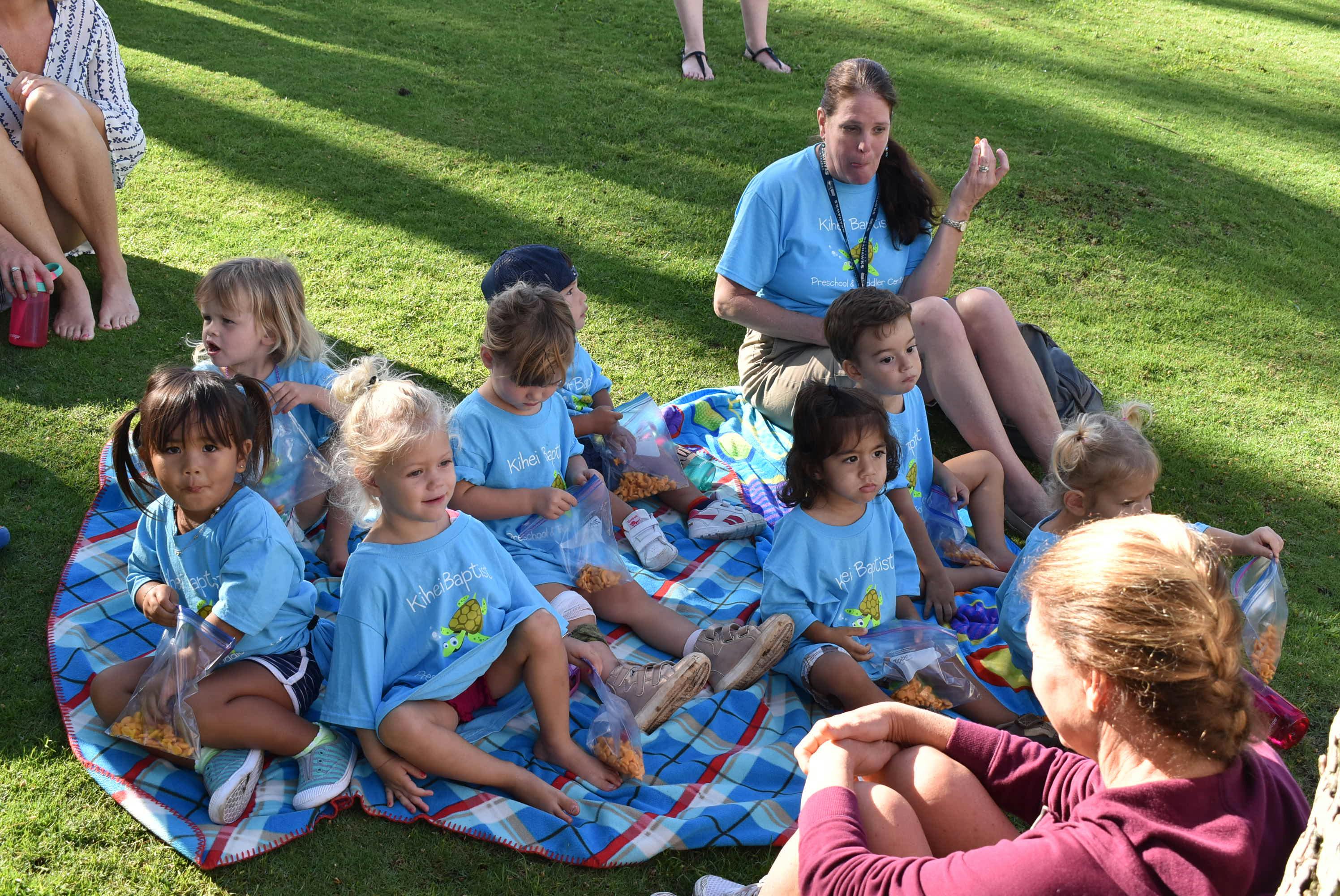 Adults and children sitting on a blanket outdoors