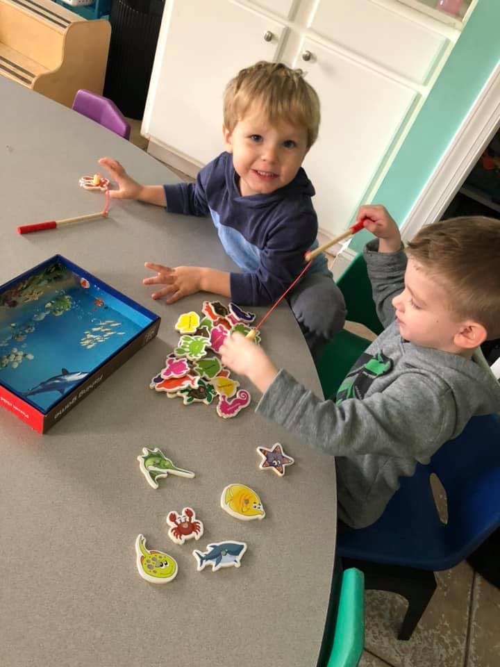 Two children playing with a magnetic fishing game at a table