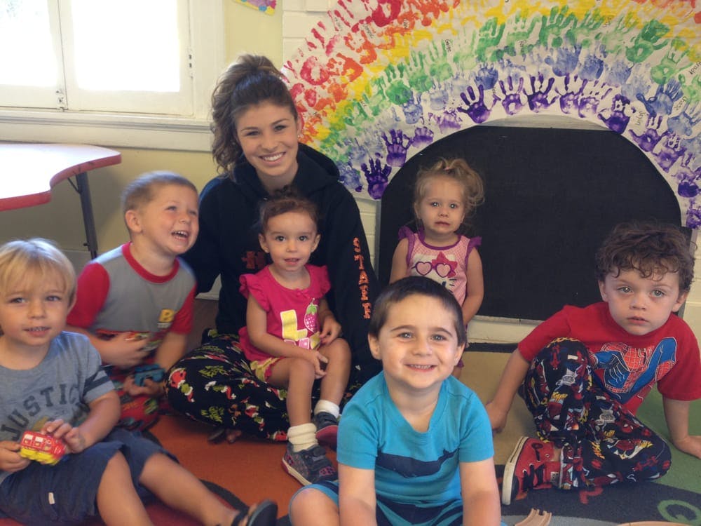 Adult and multiple children sitting on the floor in a classroom