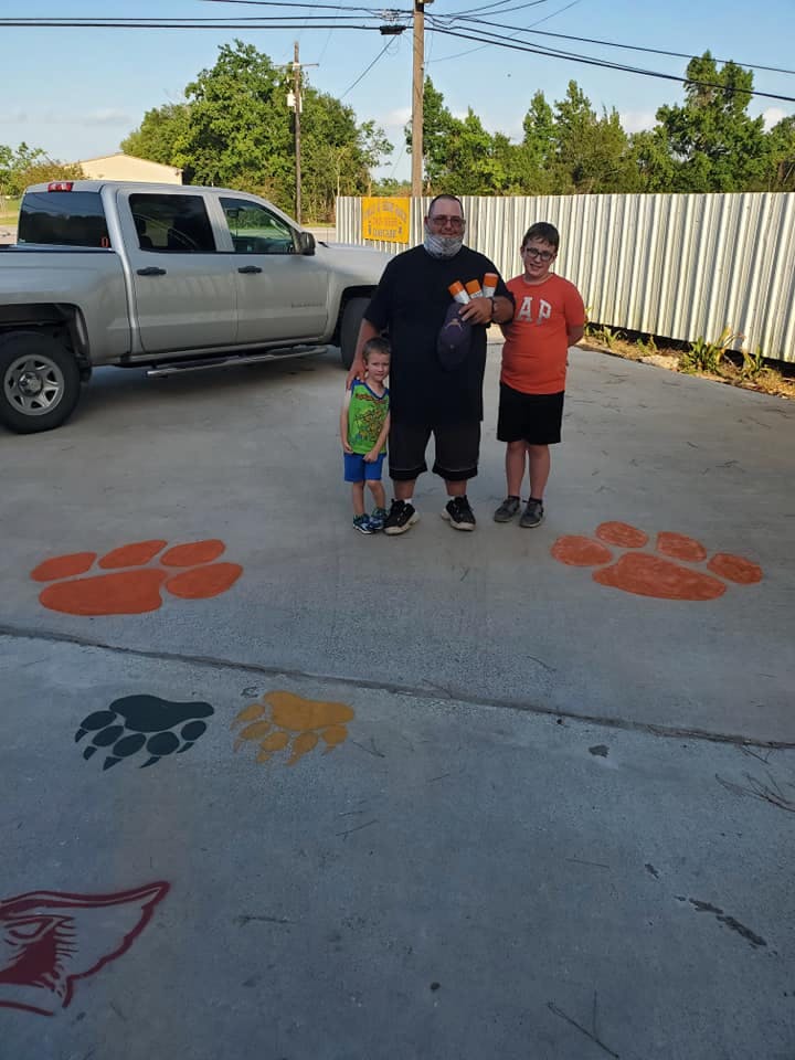 Adult and two children standing on pavement with painted paw prints