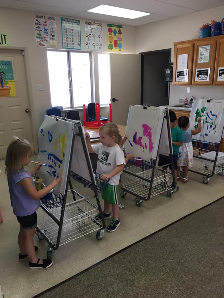 Children painting at easels in a classroom