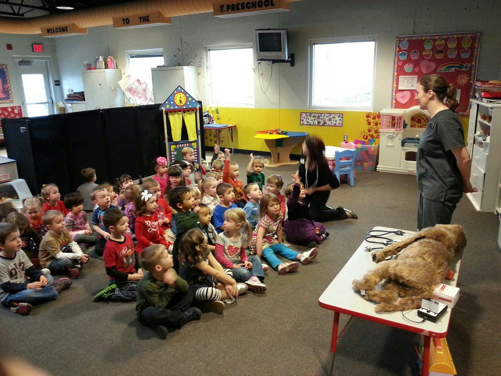 Person speaking to children sitting on floor in a classroom