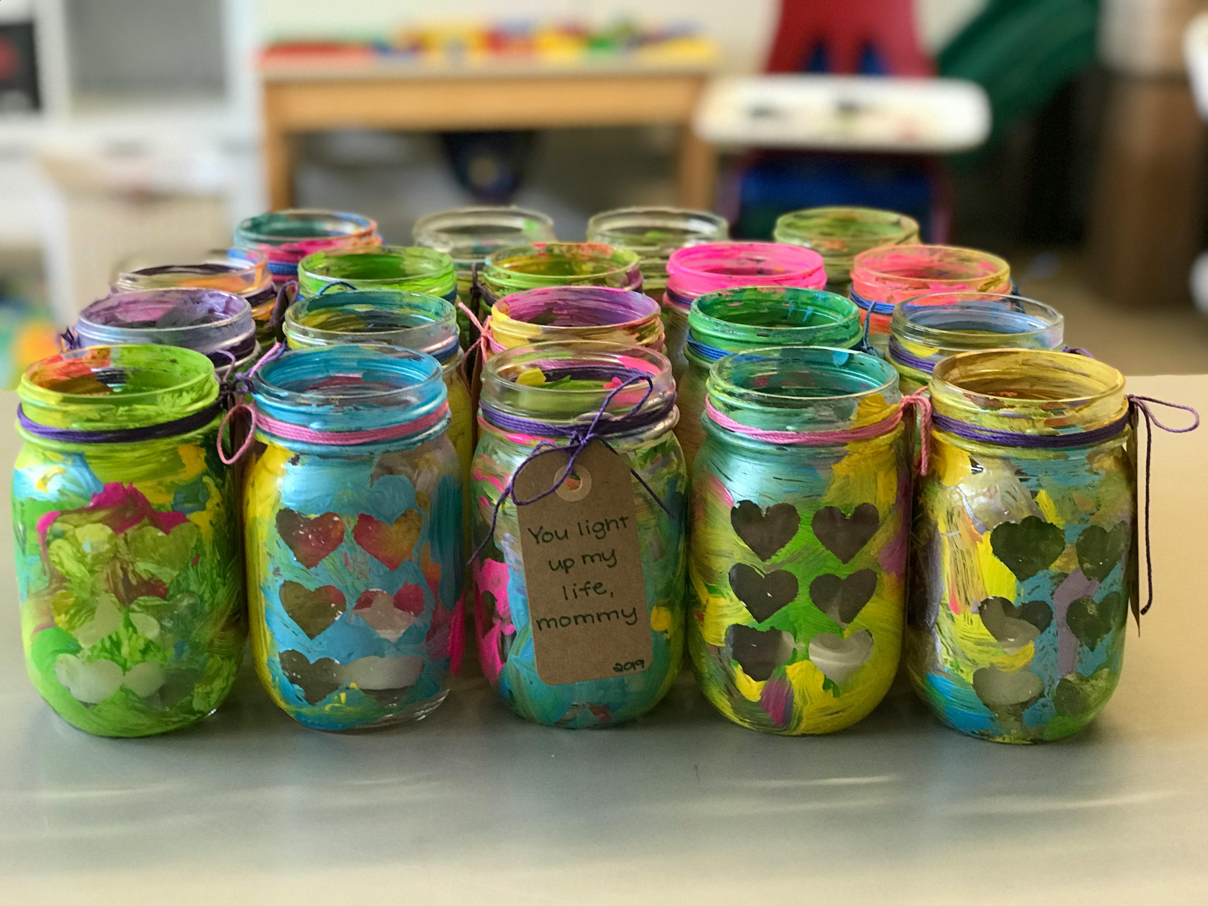 Group of colorful painted mason jars, some with heart cutouts