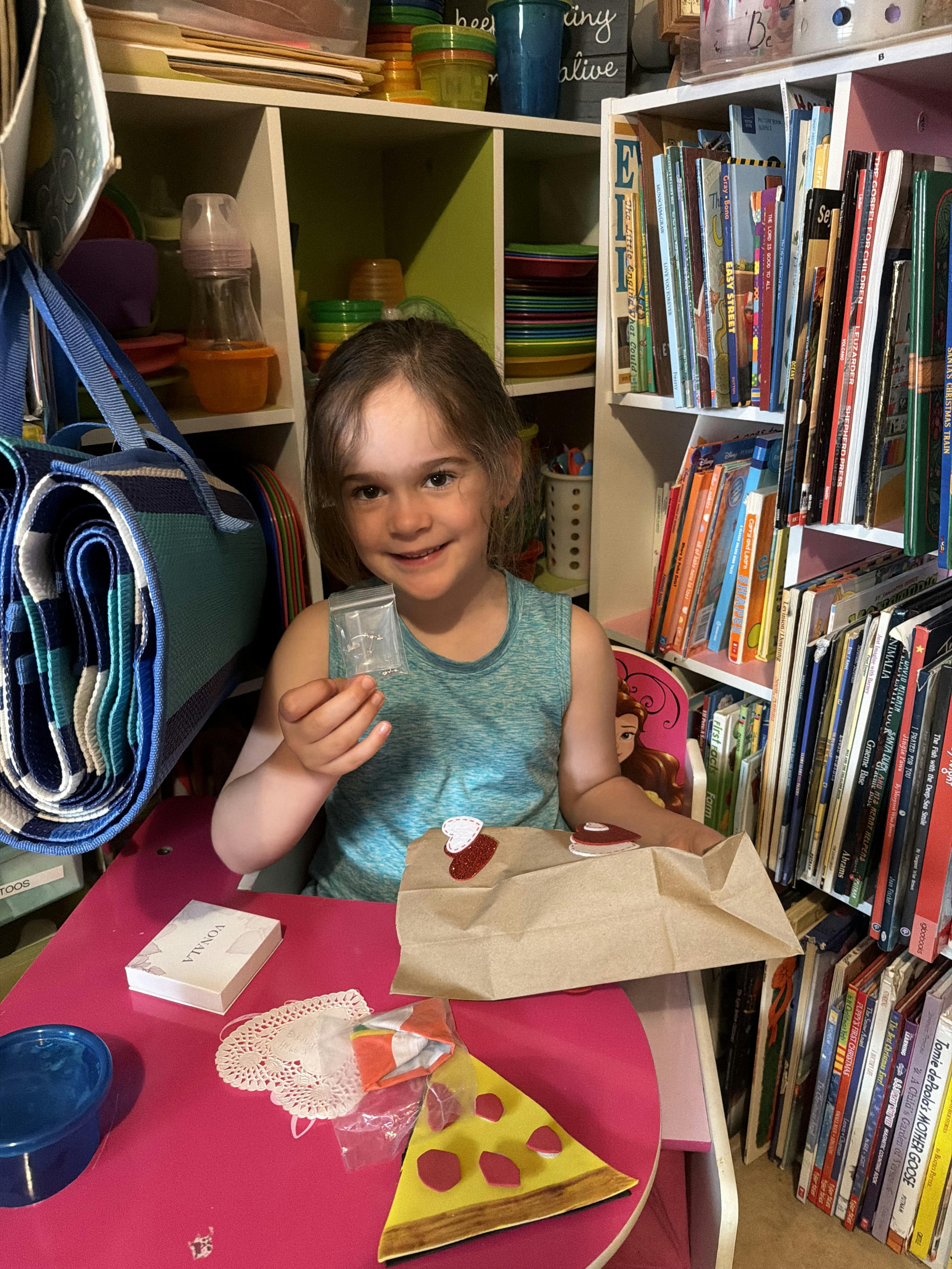 Child sitting at a table holding a small plastic bag