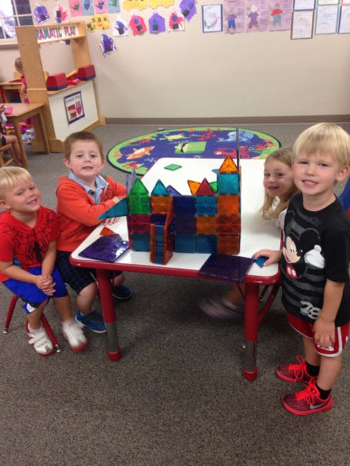 Children playing with colorful magnetic blocks at a table in a classroom