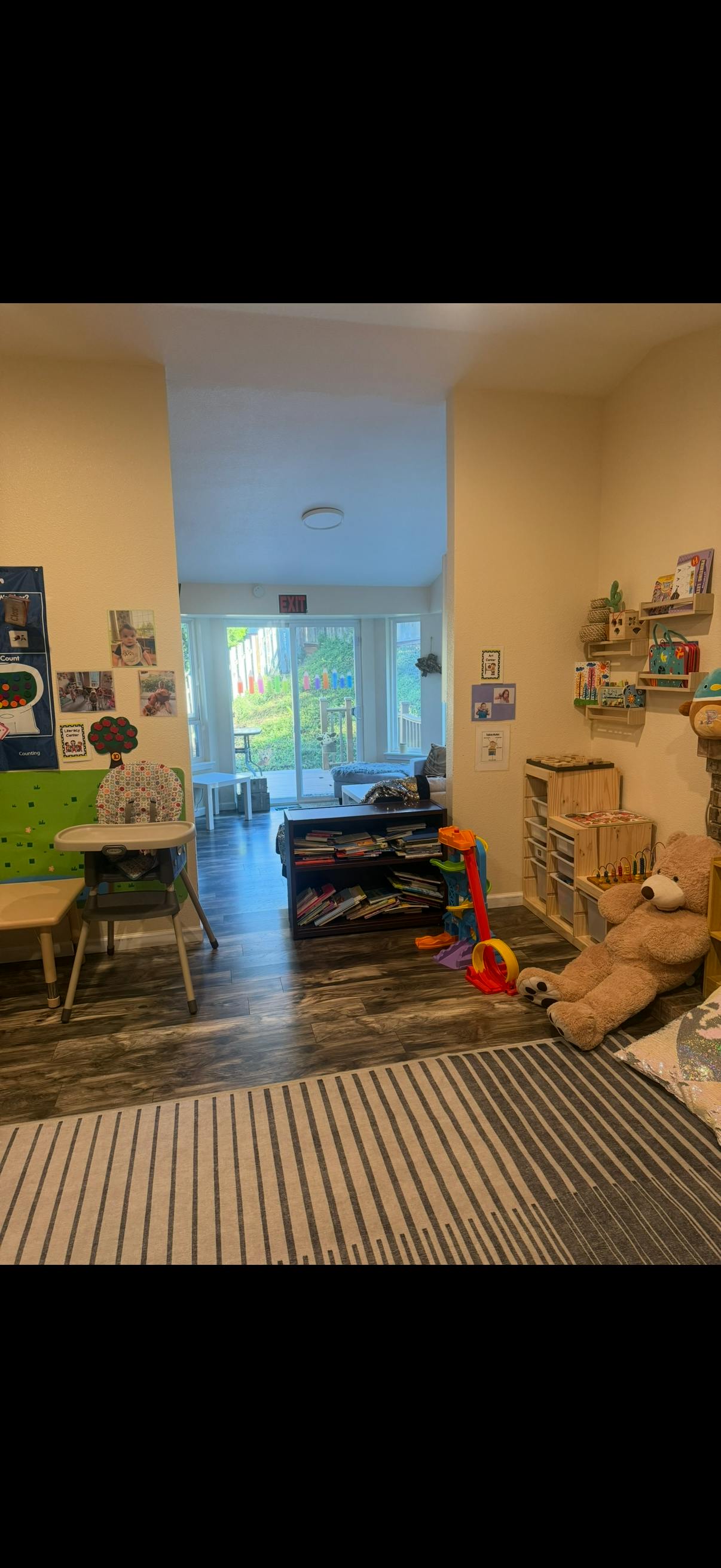 Children's playroom with toys, a high chair, and a large teddy bear