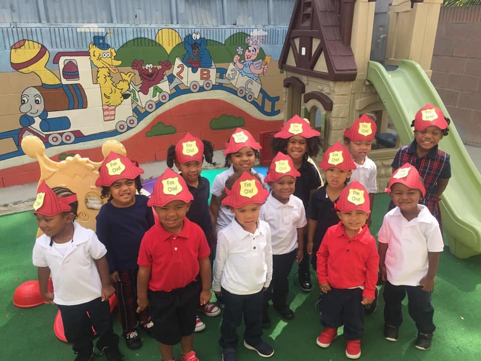 Group of children wearing red firefighter hats in a play area