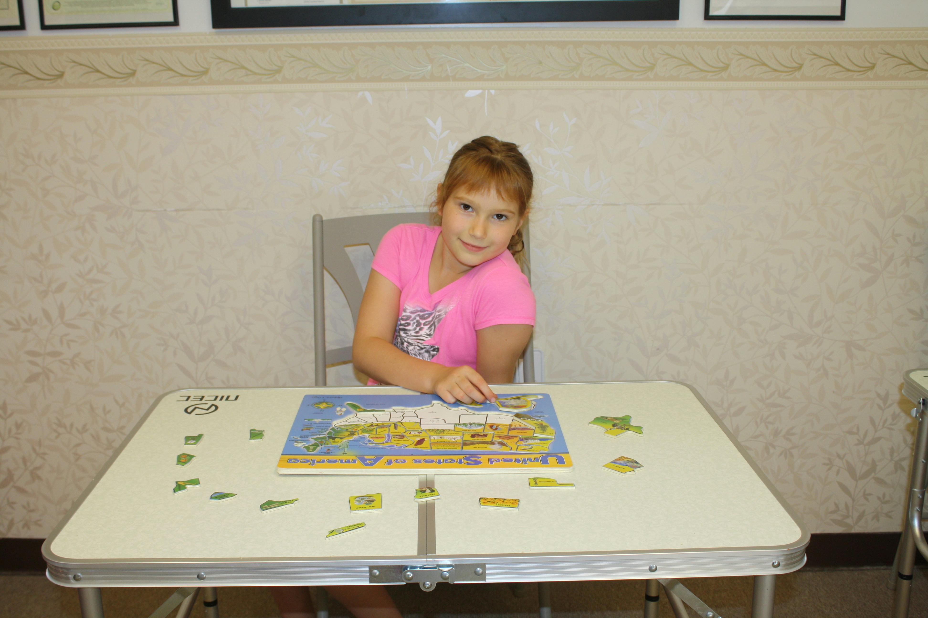 Child sitting at a table with a puzzle