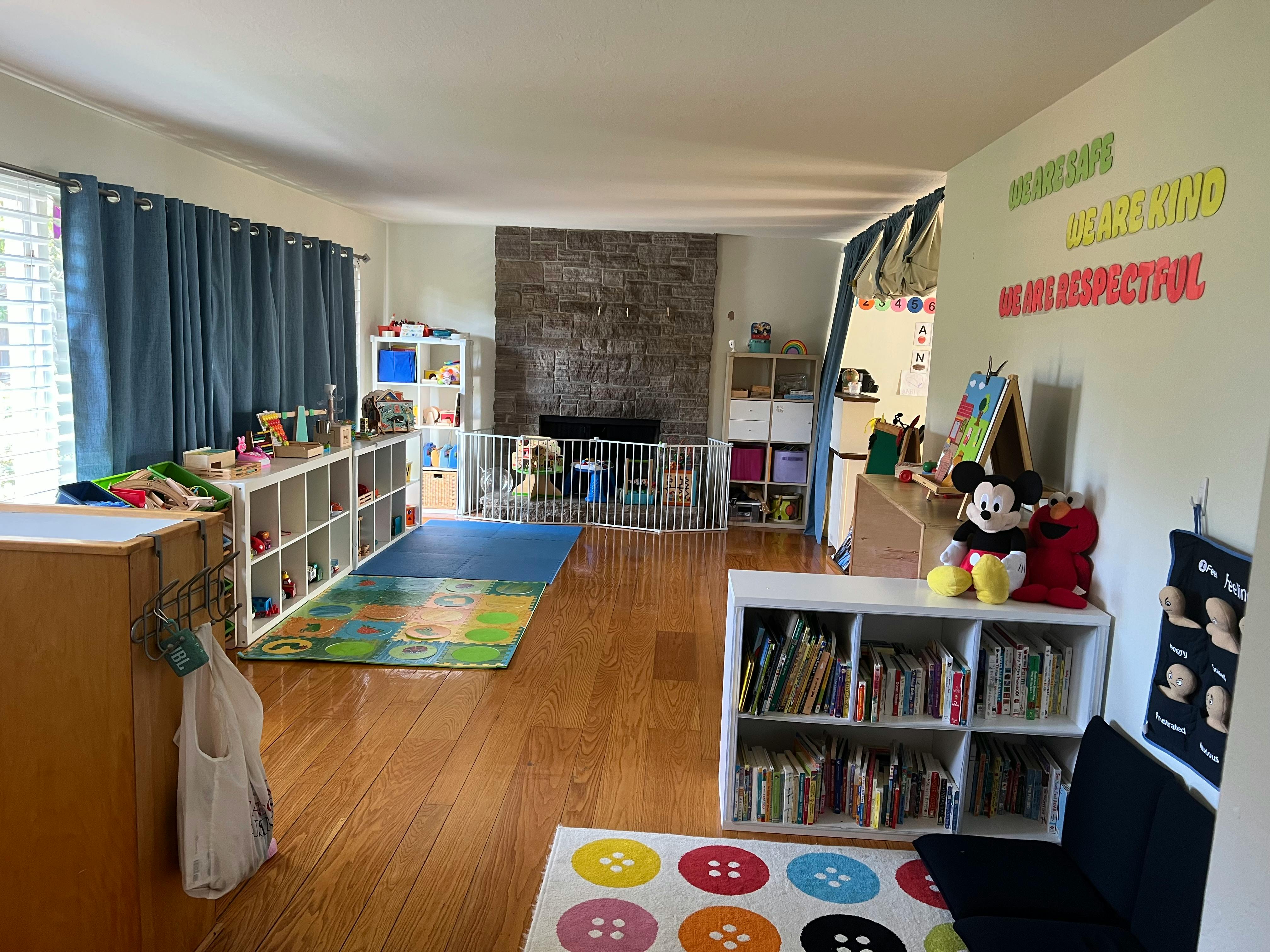 Playroom with toys, books, and a fireplace with a safety gate