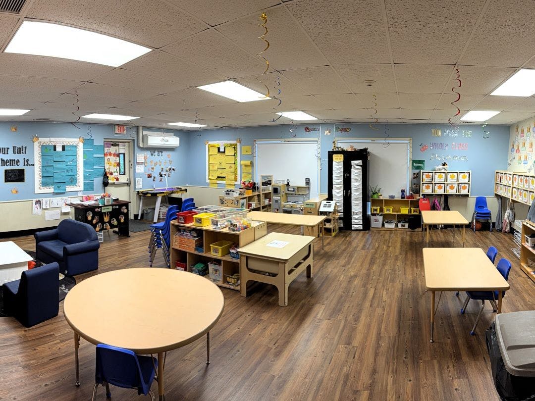 Empty classroom with small tables and chairs, and light blue walls
