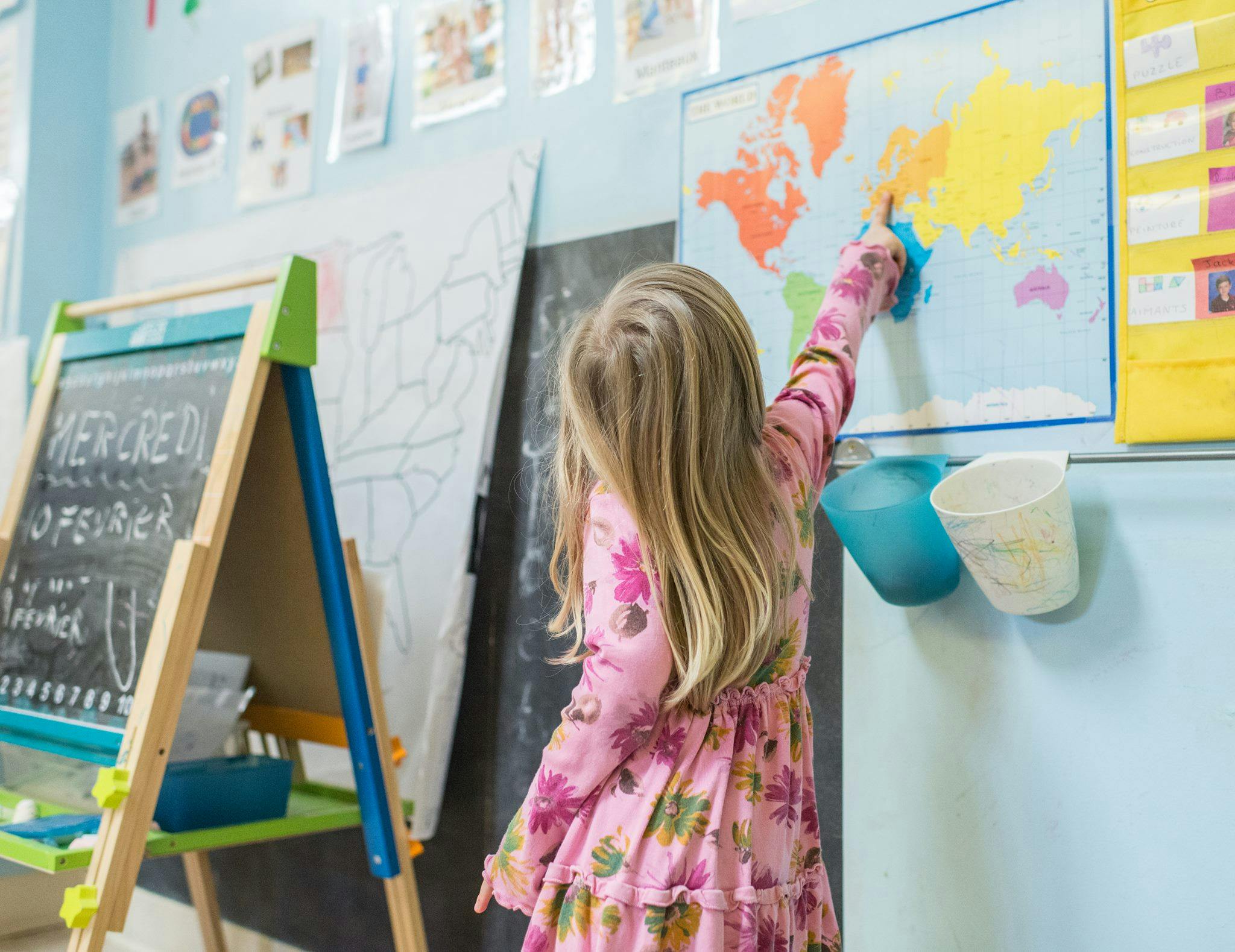 Child pointing at a world map in a classroom