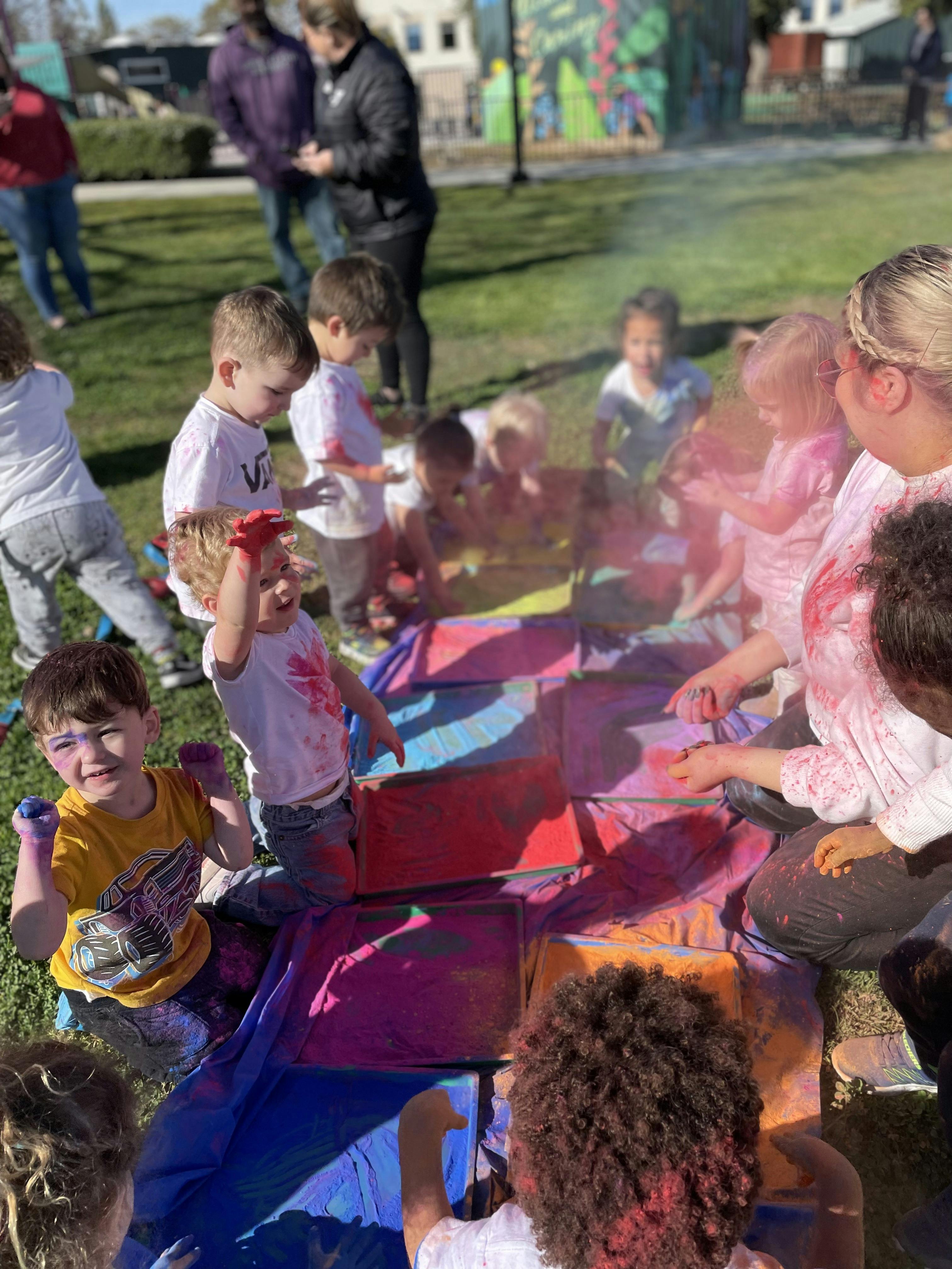Children playing with colorful powders and painting on fabric outdoors