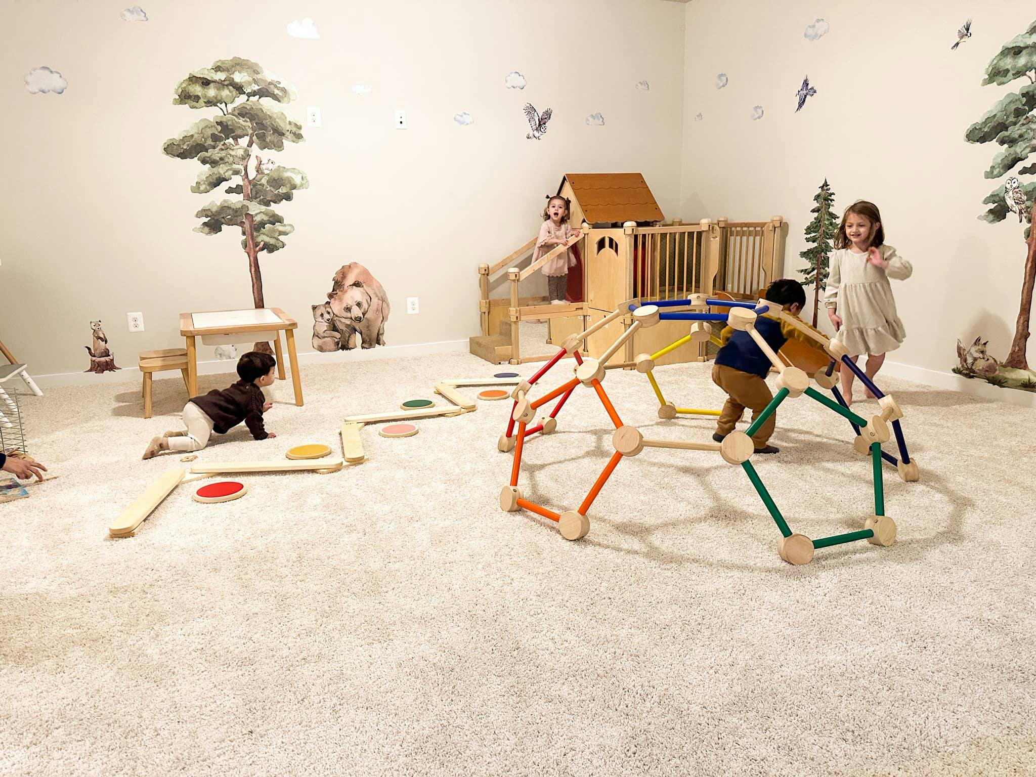 Children playing in a room with a climbing dome and wooden play structures