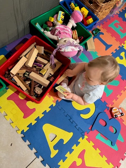 Child playing on alphabet mat with toys