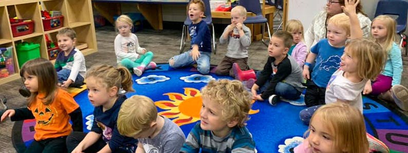 Children sitting on a rug in a classroom