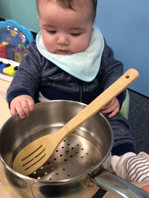 Child playing with a pot and wooden spoon