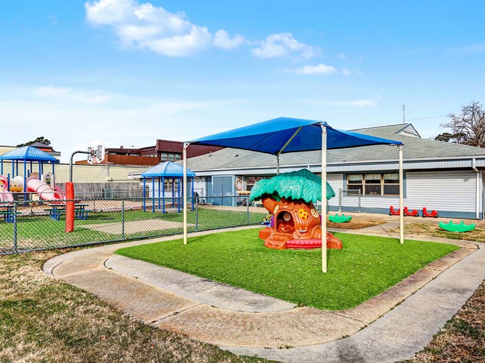 Outdoor playground with artificial grass, slides, and a playhouse
