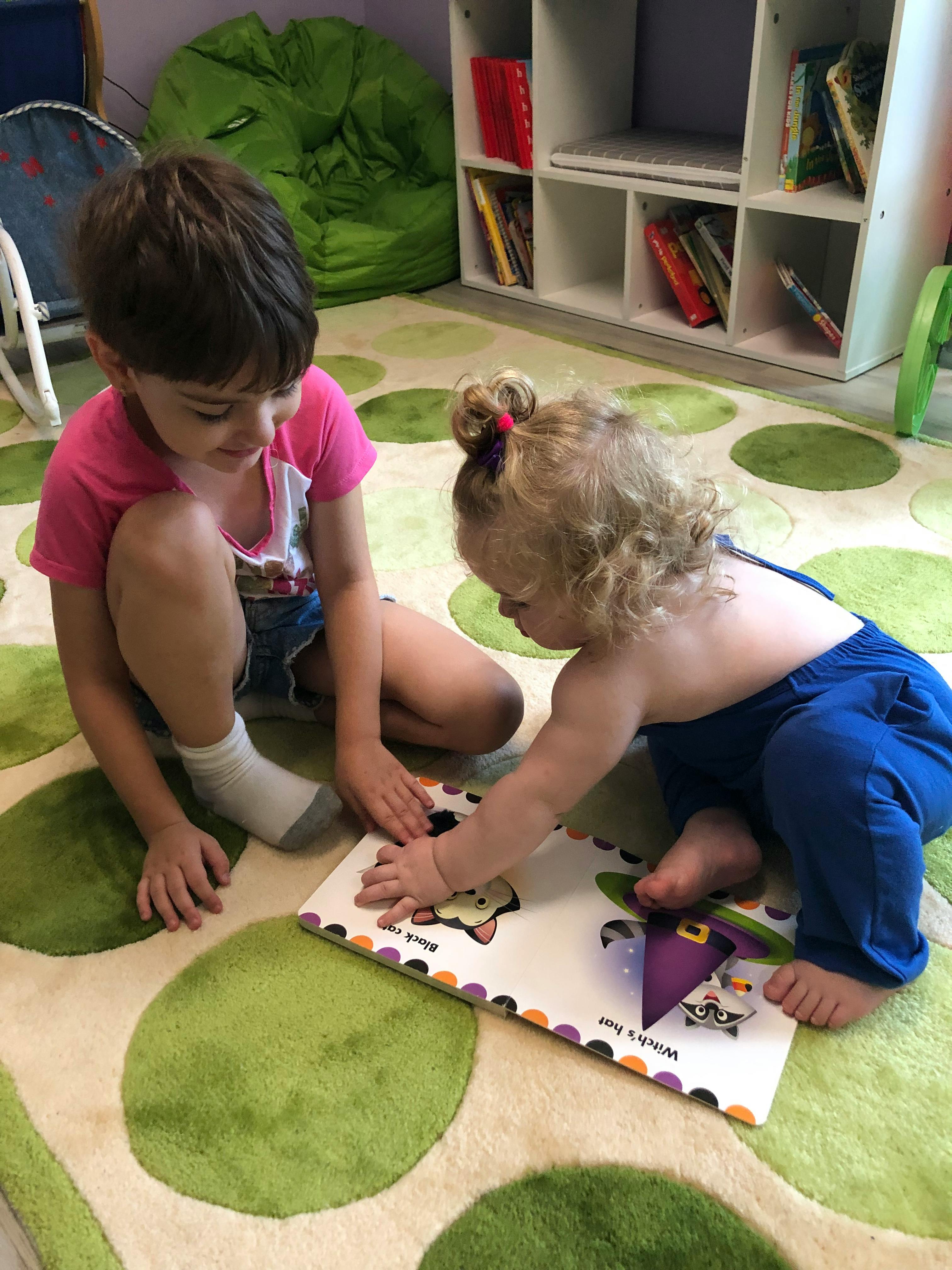 Two children on a rug looking at a book